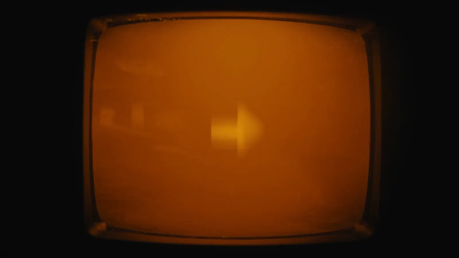 Extreme close-up of a glowing amber CRT terminal screen in a dark room