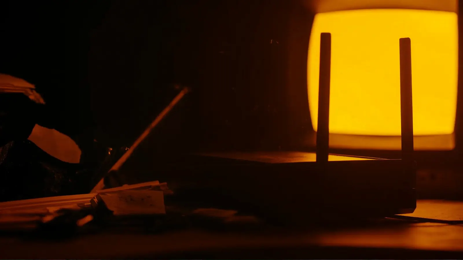 A Wi-Fi router silhouetted against the warm amber glow of a CRT monitor